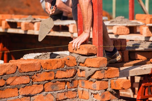 Building construction artisan hands tool laying bricks closeup cement wire wall construction