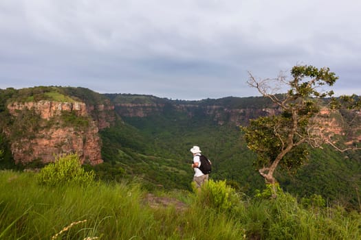 Wilderness hiker male hiking overlooking summer valley rocky cliffs gorge landscape..