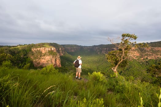 Wilderness hiker male hiking overlooking summer valley rocky cliffs gorge landscape..