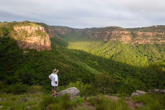Wilderness hiker male hiking overlooking summer valley rocky cliffs gorge landscape..