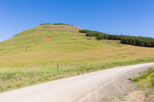 Dirt road route through farmlands fields crops hills scenic rural mountain summer terrain.