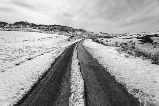Mountains Snow dirt road tracks towards hilltop in vintage black and white landscape