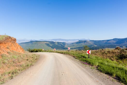 Mountains dirt road route corner through scenic rural mountain farming terrain summer holiday landscape.