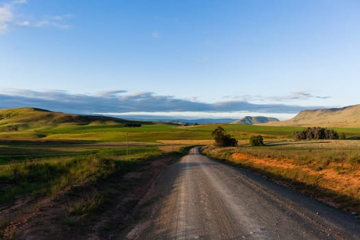 Dirt road route through scenic rural mountain farming terrain summer landscape.