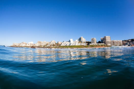 Swimming ocean water photo of Ballito Bay Ocean beach holiday apartment buildings coastline landscape.
