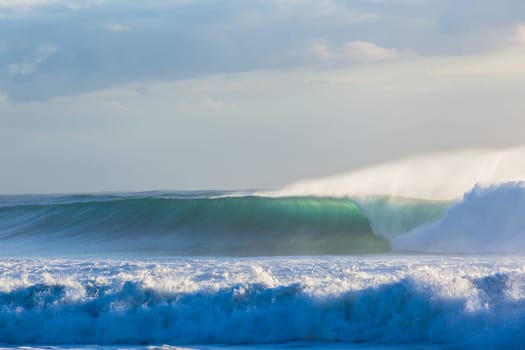 Ocean waves crashing water power towards beach from weather storms.