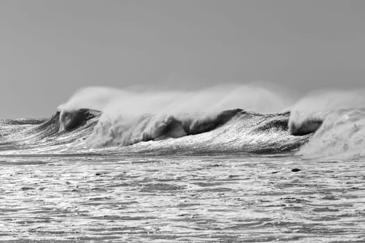 Ocean large waves crashing water power towards beach from weather storms.