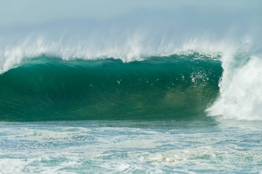 Ocean large waves crashing water power towards beach from weather storms.