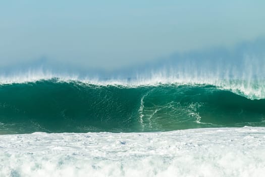 Ocean large waves crashing water power towards beach from weather storms.