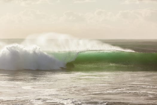 Ocean waves crashing water power towards beach from weather storms.
