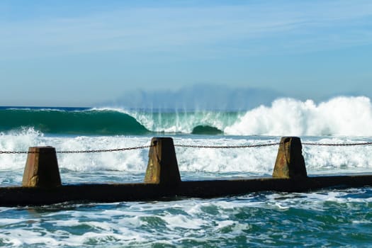 Ocean large waves crashing water power towards beach from weather storms.
