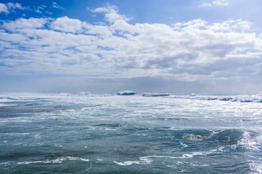 Ocean large waves crashing water power towards beach from weather storms.