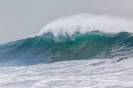 Ocean large waves crashing water power towards beach from weather storms.