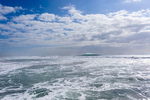 Ocean large waves crashing water power towards beach from weather storms.