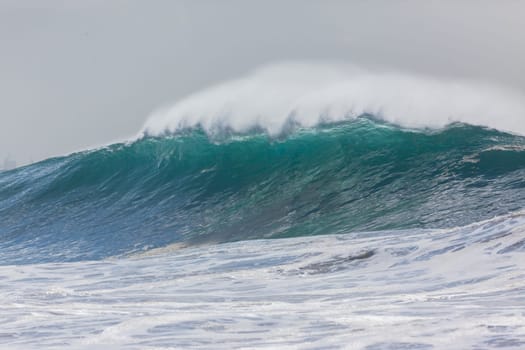 Ocean large waves crashing water power towards beach from weather storms.