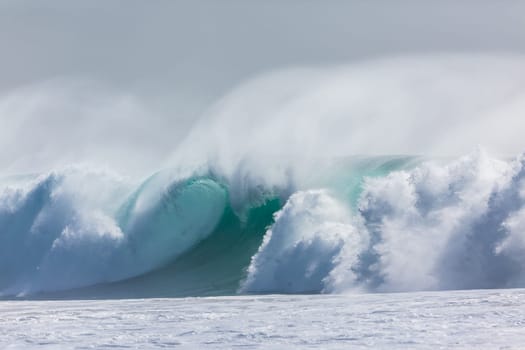 Ocean large waves crashing water power towards beach from weather storms.