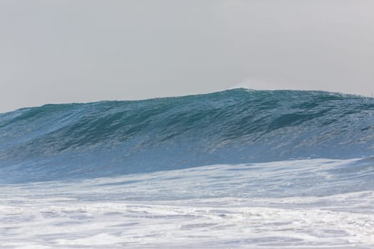 Ocean large waves crashing water power towards beach from weather storms.