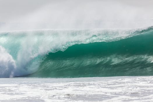 Ocean large waves crashing water power towards beach from weather storms.