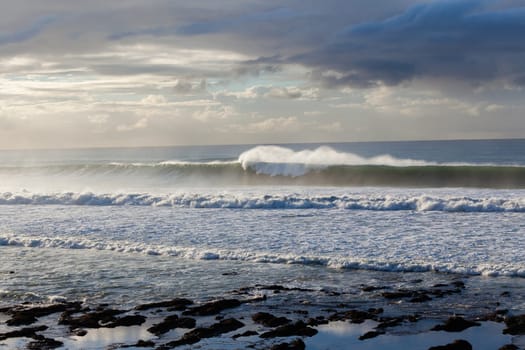 Ocean Waves crashing water power along beach rocky coastline from storm weather.