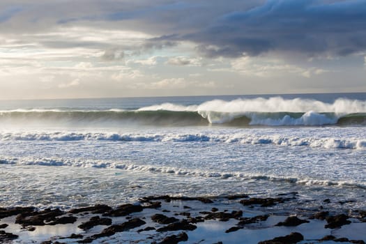 Ocean Waves crashing water power along beach rocky coastline from storm weather.