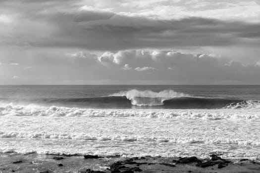 Ocean Waves crashing water power along beach rocky coastline from storm weather.