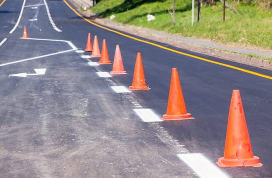 Road painting lines on new on asphalt surface with orange markers safety for vehicle traffic.