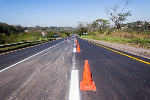 Road painting lines on new on asphalt surface with orange markers safety for vehicle traffic.