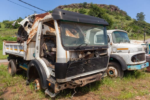 Trucks vehicles abandoned scrapped destroyed outdoors countryside.