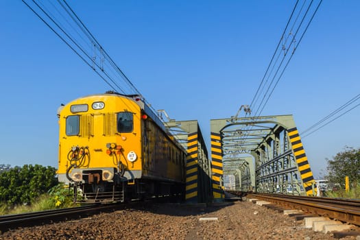 Train passenger coaches closeup on rail tracks crossing bridge to city countryside.