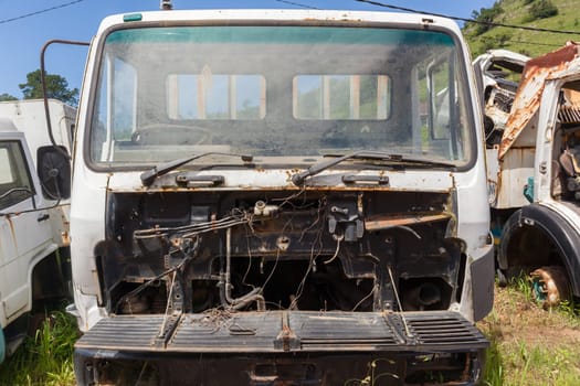 Trucks vehicles abandoned scrapped destroyed outdoors countryside.