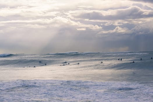 Surfers surfing out in large ocean storm waves.