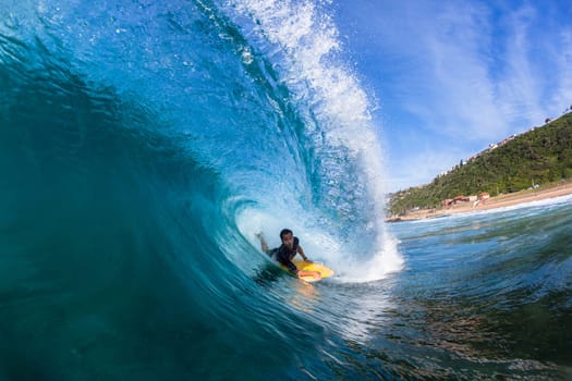 Surfing surfer body-boarder rides inside hollow ocean wave water action photo.
