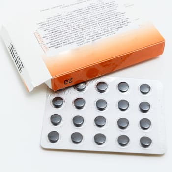 black tablets in a blister pack on white background