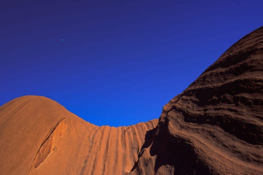 Low angle view of the striations on the surface southern of Uluru, rocks against clear blue sky, the moon in the background, Uluru Kata Tjuta National Park , Australia
