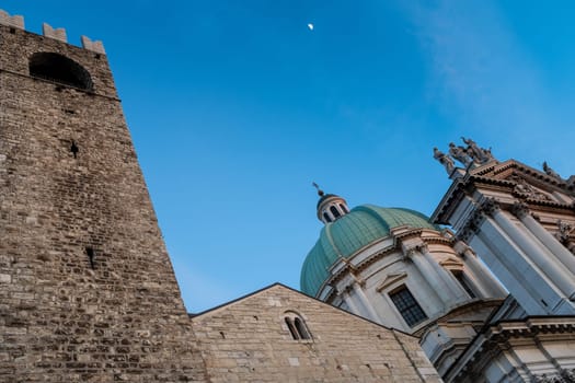 Close up shot of Broletto Palace  and the Cathedral on blue sky and the moon in background, Brescia, Lombardy, Italy