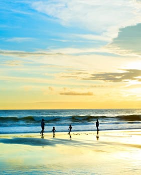 Family walking at sandy beach, sunset seascape, Bali, Indonesia