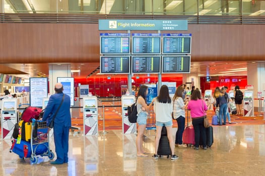 SINGAPORE - JANUARY 13, 2017: People looking at Flight information desk at Changi International airport in Singapore