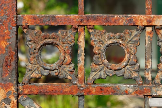 Old rusty decorated garden fence made of cast iron