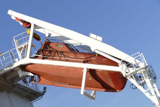 Red lifeboat hung on a cargo ship, Germany