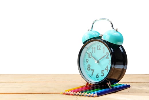Alarm clock and colored pencils on wooden table isolated over white background. Back to School concept