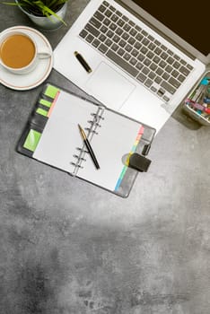 Top view of business desk with laptop, coffee, potted plant, notebook and business accessories on the office