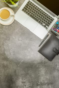 Top view of business desk with laptop, coffee, potted plant, notebook and business accessories on the office