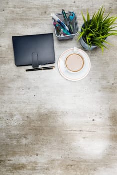 Top view of business desk with coffee, potted plant, notebook and business accessories on the office