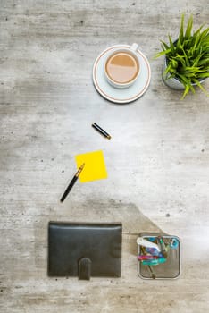 Top view of business desk with coffee, potted plant, notebook, notes paper and business accessories on the office