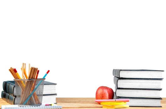 Pile of books with notes paper and pen, apple and pencils in basket container on wooden table isolated over white background. Back to School concept