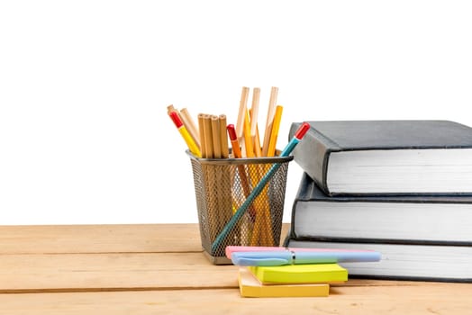 Pile of books with notes paper and pen with pencils in basket container on wooden table isolated over white background. Back to School concept