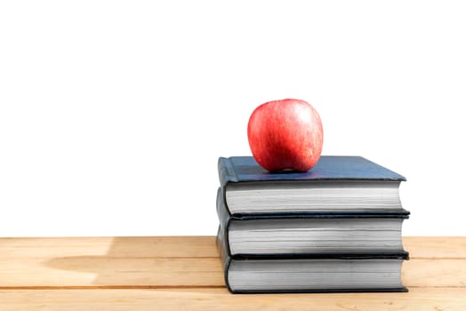 Pile of books with apple on wooden table isolated over white background. Back to School concept
