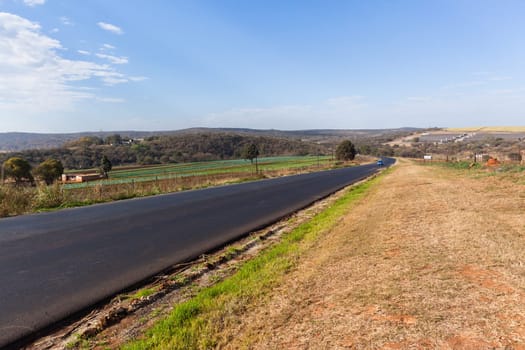 Countryside industrial new tarred asphalt surface on road  route through rural farming landscape