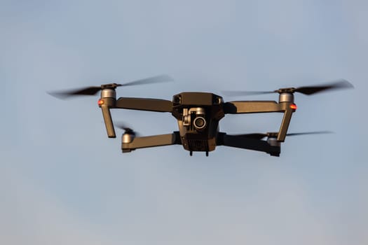 Drone aircraft with video camera flying closeup blue sky.