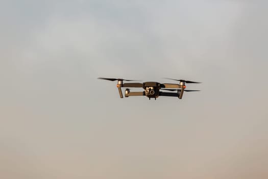 Drone aircraft with video camera flying closeup blue sky.